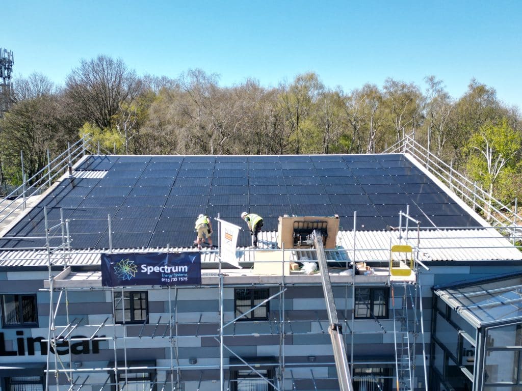 Spectrum Energy Systems installers fitting a rooftop solar array on an office building, Spectrum banner on the scaffold