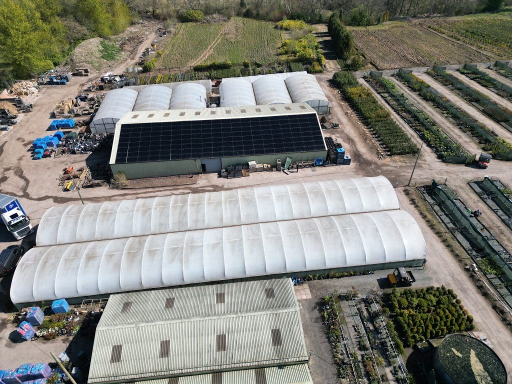 Aerial view of a farm nursery with all-black solar panels covering the barn roof, installed by Spectrum Energy Systems