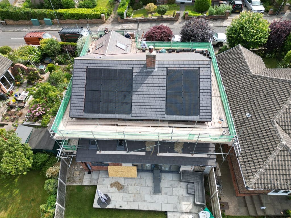 New-build home with rooftop solar panels, scaffolding still in place, aerial view