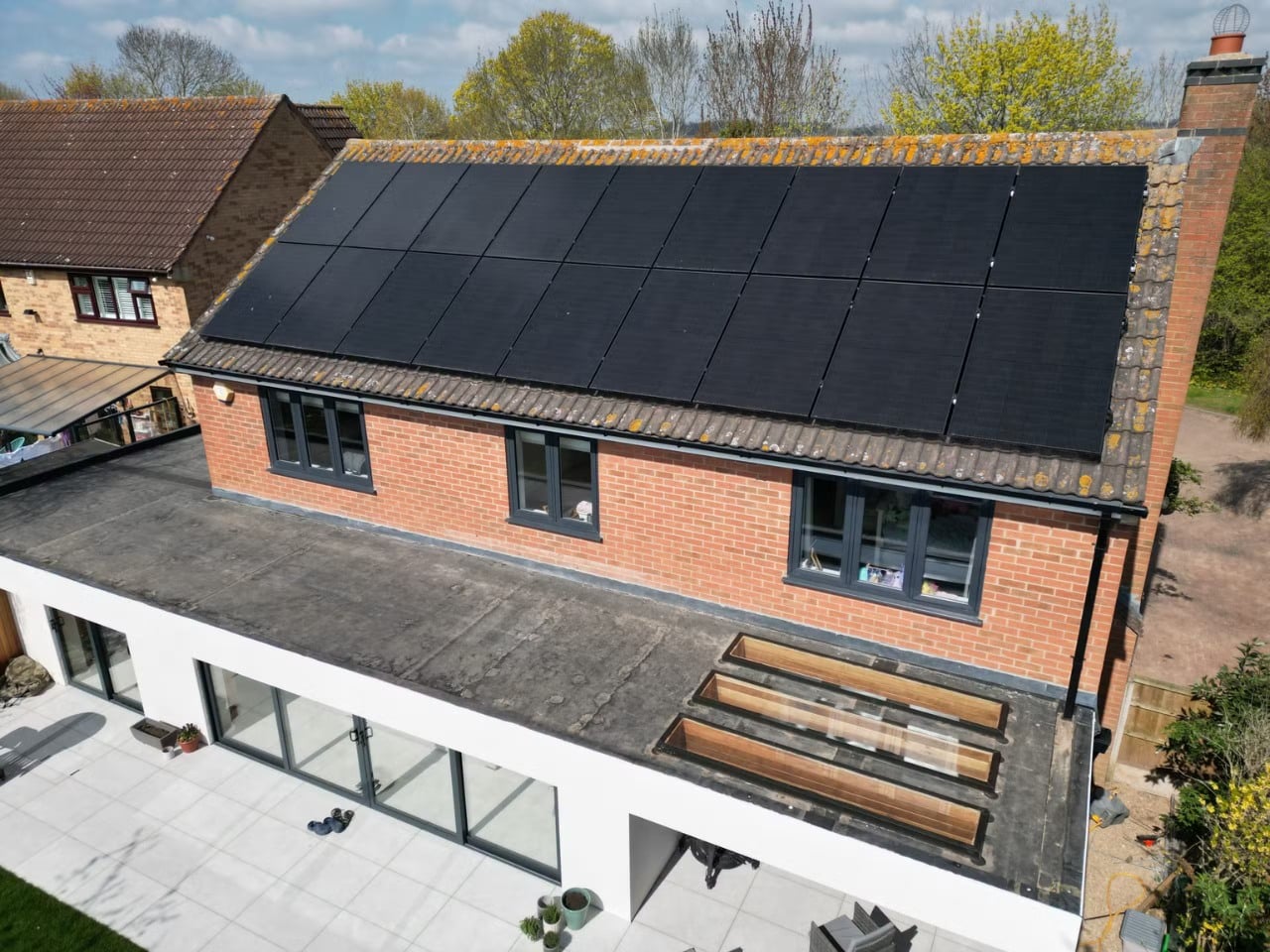 All-black solar panels fitted by Spectrum Energy Systems on the rear roof of a detached brick house