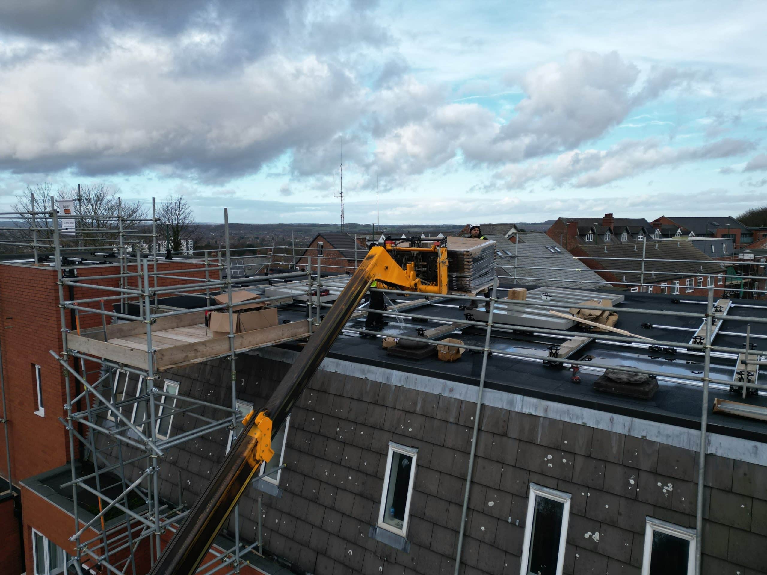 18-metre telehandler lifting JA Solar panels to flat roof during commercial solar installation at Johns of Nottingham