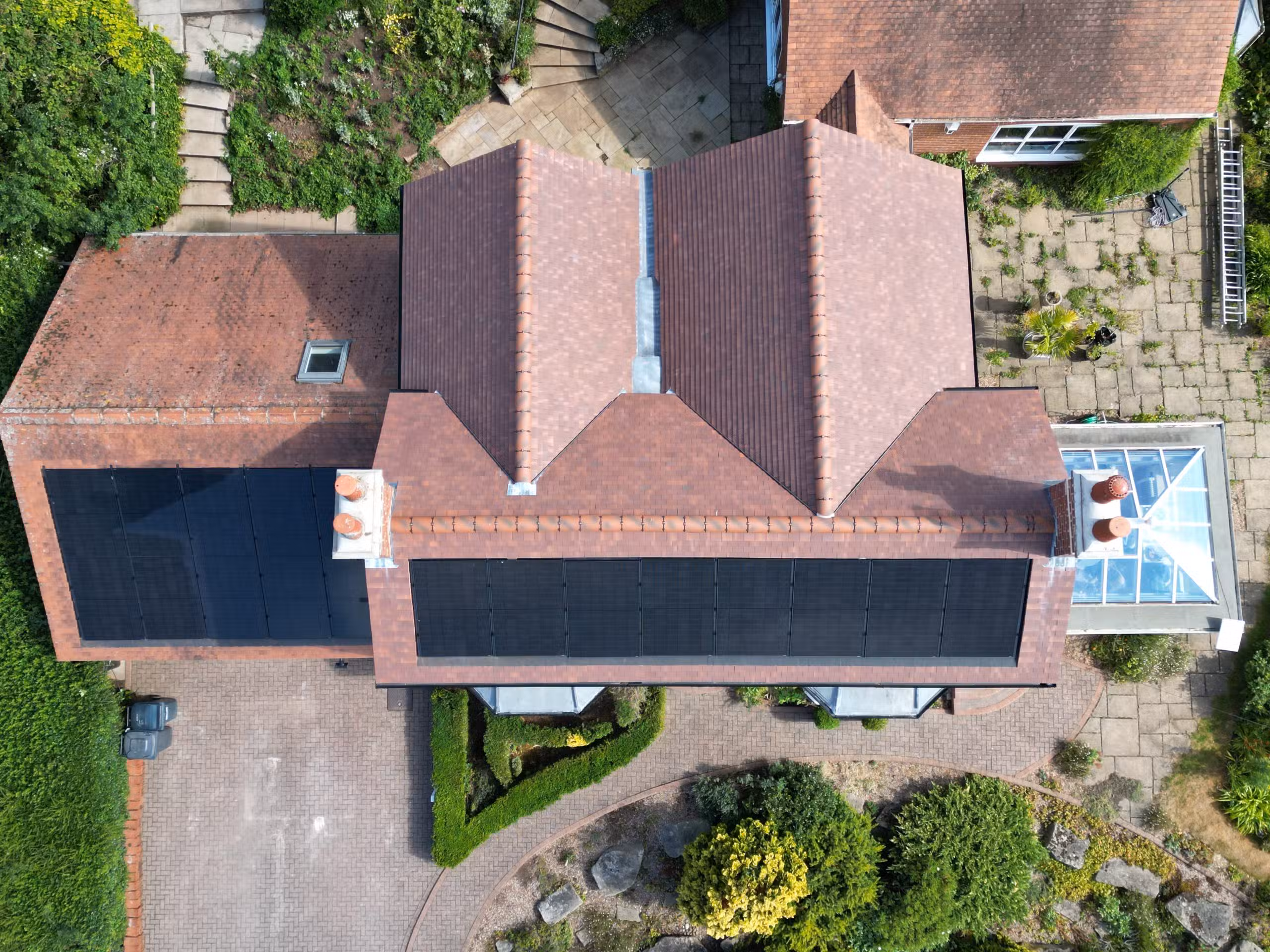 Aerial drone view of in-roof solar installation spanning main house and garage at Woodborough residential property