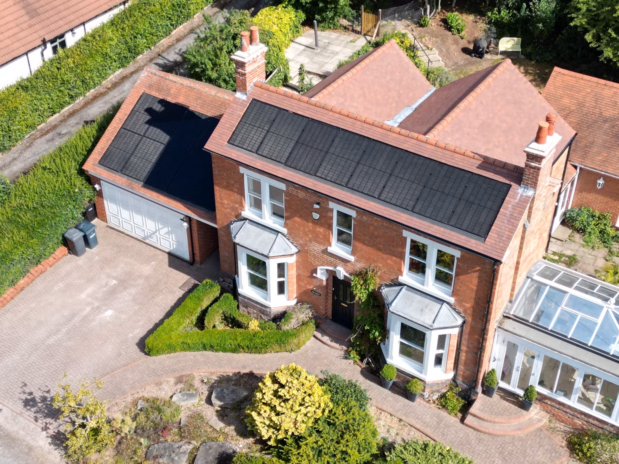 Aerial drone view of in-roof solar panel array on main house and garage roof in Woodborough, Nottingham