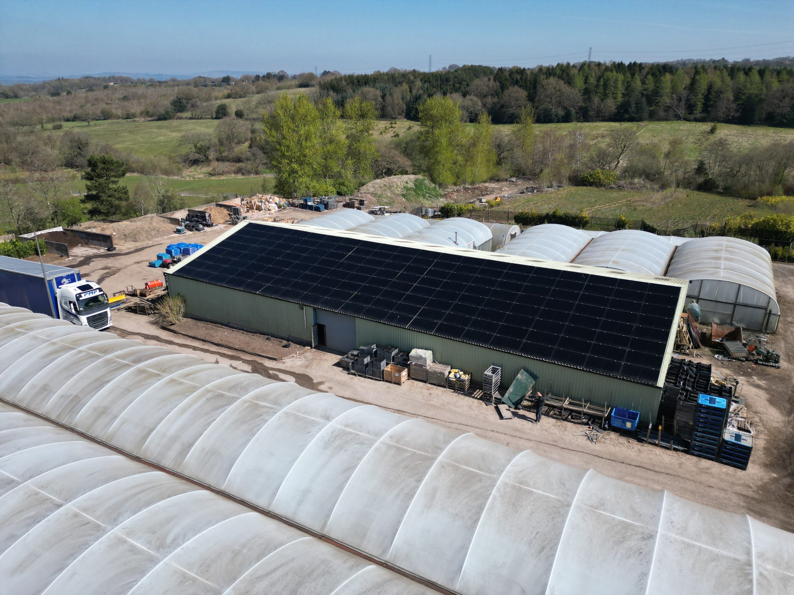 Drone overview of Aiko 455W solar panel array on trapezoidal metal roof at Jacksons Nurseries