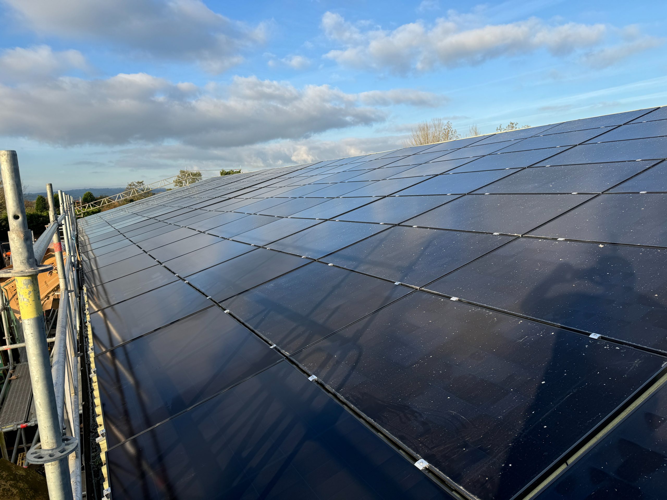 Edge detail of completed Aiko 455W solar panel array on trapezoidal metal roof at Jacksons Nurseries