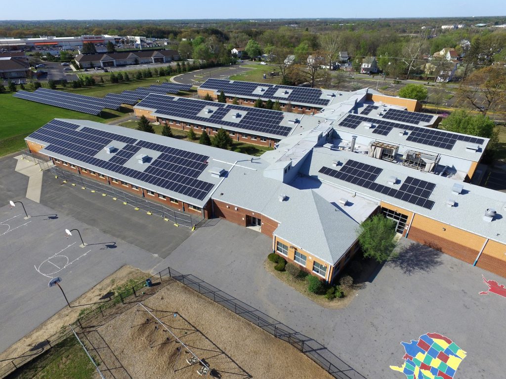 Aerial view of solar panels installed across the roofs of a school campus