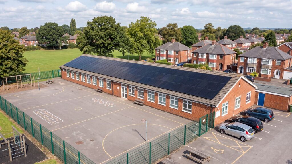 Aerial view of a red brick primary school with all-black solar panels across its roof