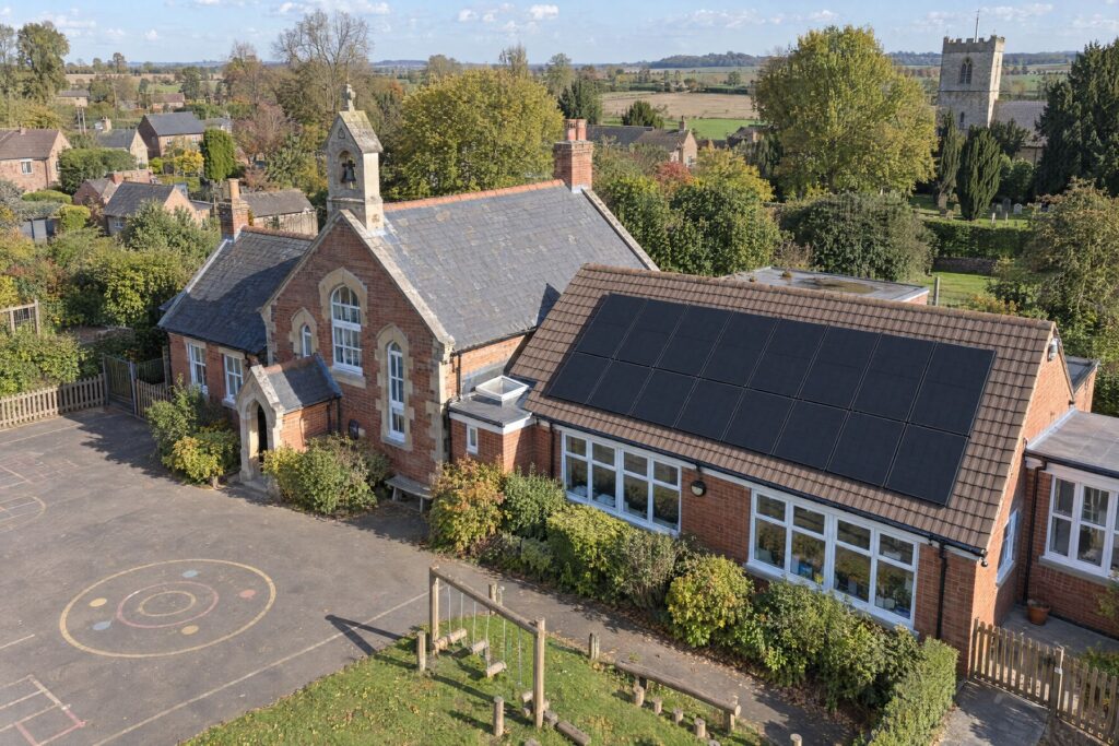 Aerial view of a village primary school with all-black solar panels on the classroom roof
