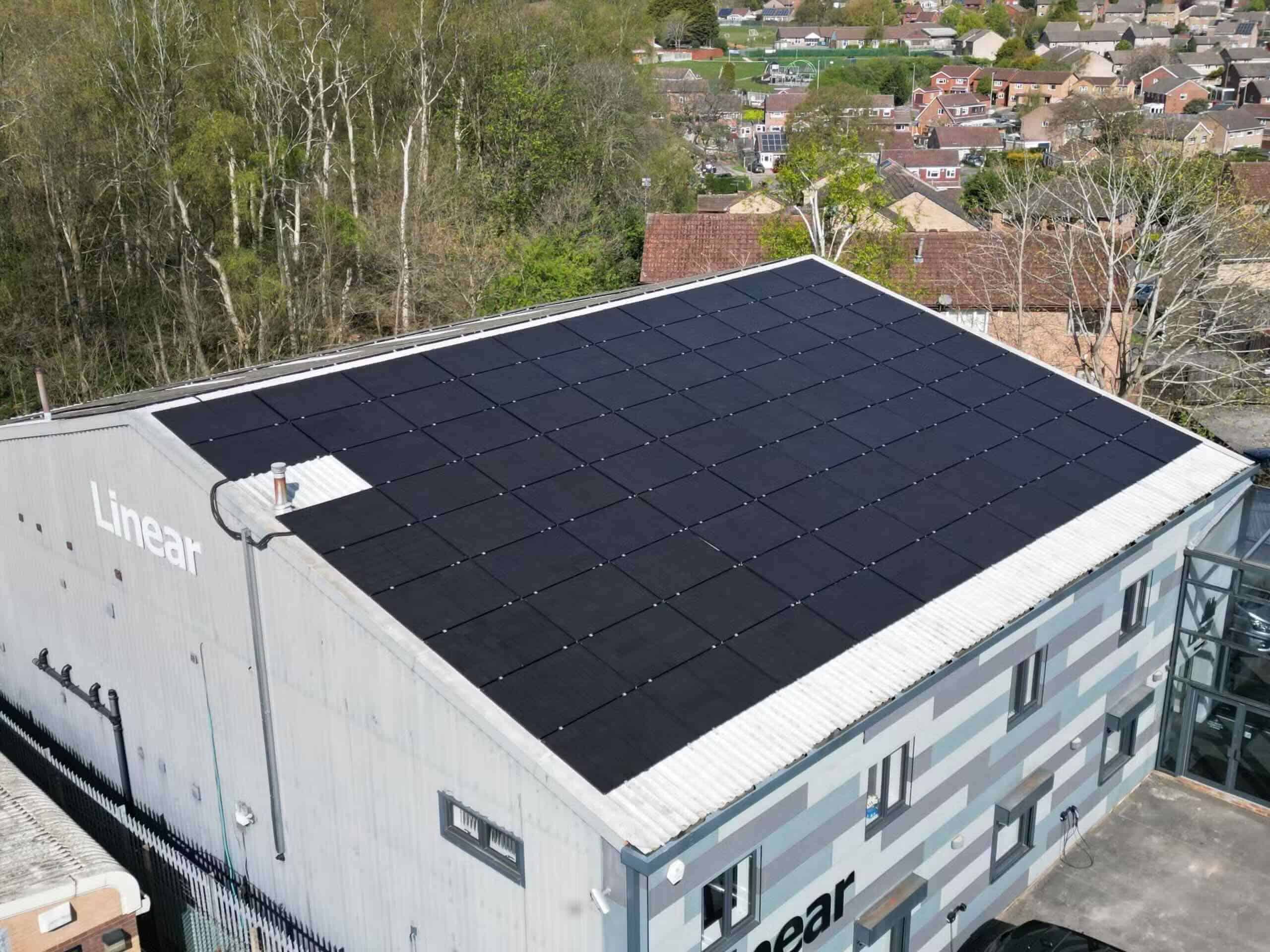 Black solar panels covering the flat roof of a commercial building, solar installers serving Chellaston